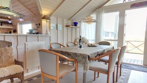 A cozy dining area with a wooden table and chairs, a refrigerator, and a view of the outdoors.