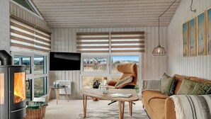 A cozy living room with a fireplace, a sofa, a coffee table, and a TV. - "Galmand" - 300m from the sea by Interhome (Lemvig)