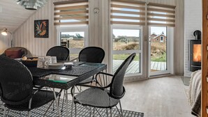 A cozy dining area with a table and chairs, a fireplace, and large windows with shutters. - "Galmand" - 300m from the sea by Interhome (Lemvig)