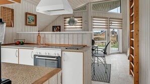 A modern kitchen with a central island, a built-in oven, and a hanging light fixture. - "Galmand" - 300m from the sea by Interhome (Lemvig)