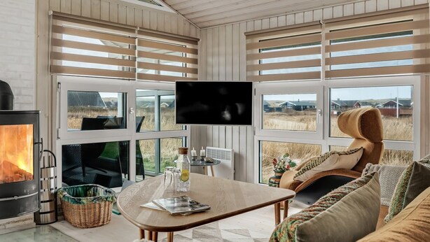 A cozy living room with a fireplace, large windows, and a comfortable seating area. - "Galmand" - 300m from the sea by Interhome (Lemvig)