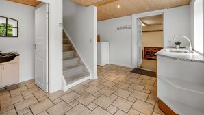 A modern kitchen with a built-in sink, a staircase leading to another room, and a wooden ceiling. - "Wilmar" - 1km to the fjord by Interhome (Vemb)