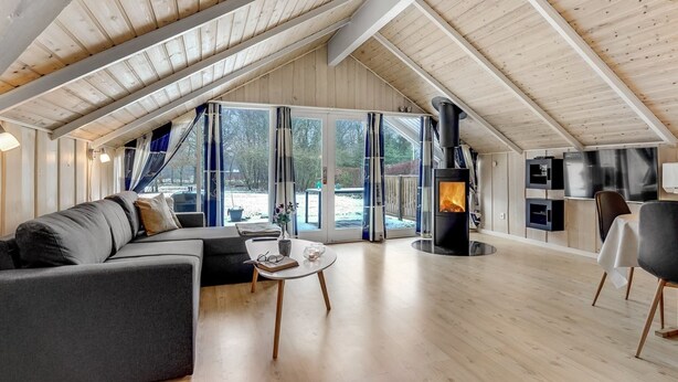 A spacious loft with a high ceiling, a cozy seating area with a sofa and coffee table, a fireplace, and a large window offering a view of the outdoors.