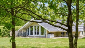 A house with a large glass door, a covered patio, and a lawn.