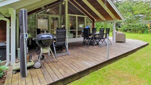 A covered outdoor deck with a grill, chairs, and a glass enclosure. - "Ellica" - 50km from the sea by Interhome (Give)