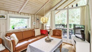 A cozy cabin interior with a wooden ceiling, a brown leather sofa, a dining table, and a television. - "Ellica" - 50km from the sea by Interhome (Give)