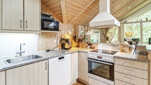 A modern kitchen with wooden cabinets, a built-in microwave, a stove, and a large window providing natural light. - "Ellica" - 50km from the sea by Interhome (Give)