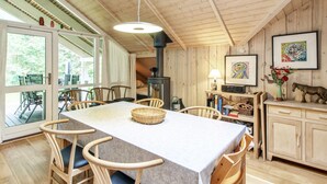 A cozy cabin interior with a large dining table, wooden chairs, a fireplace, and a view through the glass doors. - "Ellica" - 50km from the sea by Interhome (Give)