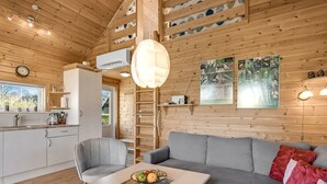 Een gezellig interieur van een chalet met een eethoek, bank en keuken.