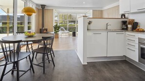Een moderne keuken met witte kasten, een centraal eiland en een eetgedeelte met een ronde tafel en stoelen.