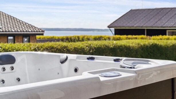 Een hottub met uitzicht op een huis en een waterlichaam.