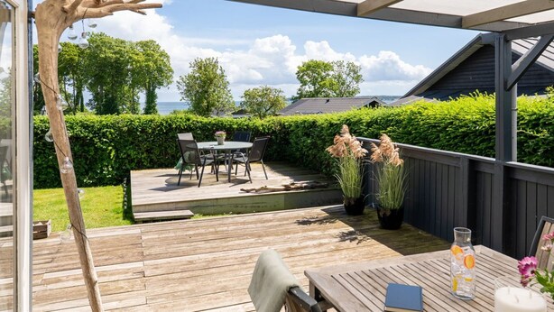 Eine Außenpatio mit Holzterrasse, einem Tisch mit Stühlen und Blick auf das Meer.
