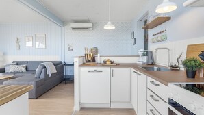 Eine moderne Küche mit weißen Schränken, einer Holz Arbeitsplatte und Pendelleuchten.
