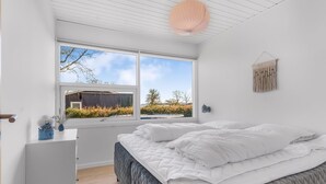 Ein Schlafzimmer mit Bett, Schminktisch, Fenster und einer Wandleuchte.