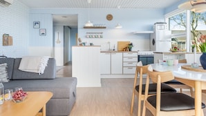 Eine moderne Küche mit weißen Schränken, einer zentralen Kochinsel und einem Essbereich mit Tisch und Stühlen.