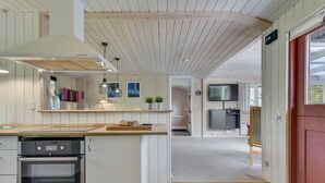 Een moderne keuken met een ingebouwde oven, een houten aanrecht en hanglampen.