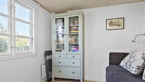Une pièce avec un meuble bleu clair doté de portes en verre, un canapé gris agrémenté de coussins à motifs floraux et un tableau encadré accroché au mur.