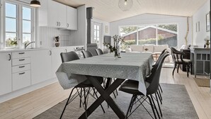 Une cuisine moderne avec des meubles blancs, un coin repas comprenant une table et des chaises, et une vue sur l’extérieur.