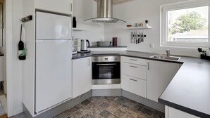 Een moderne keuken met witte kasten, een roestvrijstalen fornuis en een groot raam dat voor natuurlijk licht zorgt.