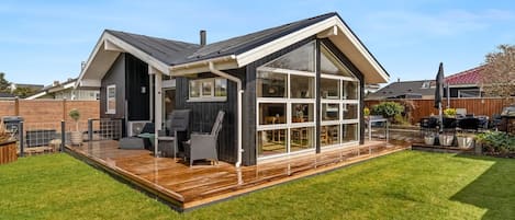 A modern house with a large deck, a covered outdoor seating area, and a well-maintained lawn.