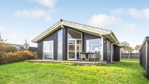 A modern two-story house with a large front porch, a covered patio, and a well-maintained lawn.
