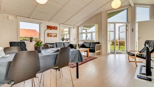 A spacious living area with a large dining table, multiple chairs, a sofa, and a television.