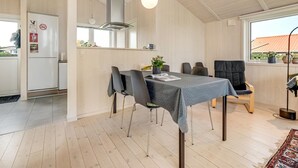 A modern kitchen with a dining area, featuring a large table, chairs, and a hanging light fixture.