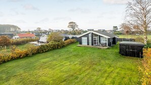 A modern house with a large lawn, a shed, and a view of a residential area.