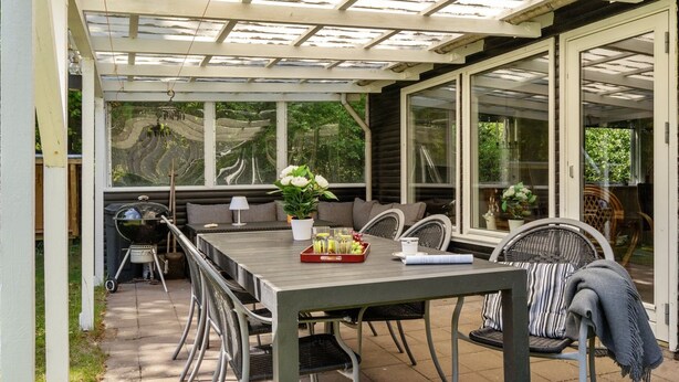 A covered patio area with a table and chairs, a grill, and a potted plant. - "Ulrike" - 600m to the fjord by Interhome (Ulfborg)