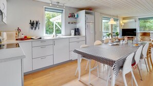 A modern kitchen with white cabinets, a dining area with a patterned tablecloth, and a TV in the living area. - "Ulrike" - 600m to the fjord by Interhome (Ulfborg)