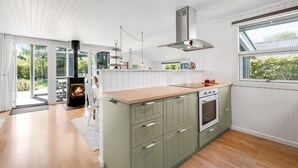 Eine moderne Küche mit Kochinsel, integriertem Backofen und großem Fenster.