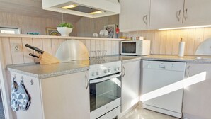 Ett kompakt kök med spis, ugn, mikrovågsugn och diskmaskin.