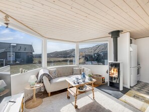 Um quarto acolhedor com sofá, mesa, lareira e amplas janelas com vista para a paisagem.