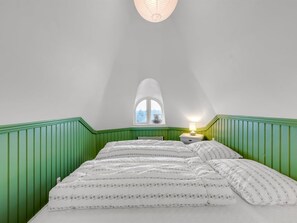A bedroom with a bed, a nightstand, a lamp, and a window.