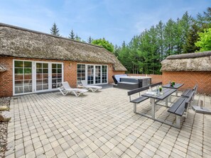 Un espace patio agrémenté d’un bâtiment à toit de chaume, de sièges extérieurs et d’un jacuzzi.