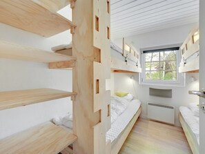 Une petite pièce avec des lits superposés, une fenêtre et un radiateur encastré.