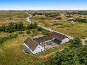 A white building with a thatched roof, surrounded by a rural landscape with scattered houses and a winding road. - "Cornelius" - 900m from the sea by Interhome (Ulfborg)