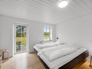 A bedroom with a large bed, a window, and a door leading to an outdoor area.