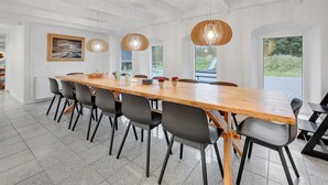 A modern dining area with a long wooden table, black chairs, and three pendant lights. - "Cornelius" - 900m from the sea by Interhome (Ulfborg)