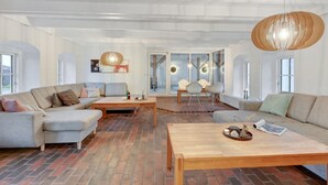A spacious living room with a brick floor, two sofas, a wooden coffee table, and a hanging light fixture. - "Cornelius" - 900m from the sea by Interhome (Ulfborg)