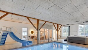 An indoor swimming pool with a blue slide, wooden beams, and a modern interior design. - "Cornelius" - 900m from the sea by Interhome (Ulfborg)