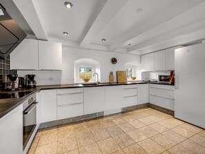 A modern kitchen with white cabinetry, a granite countertop, and a built-in oven.