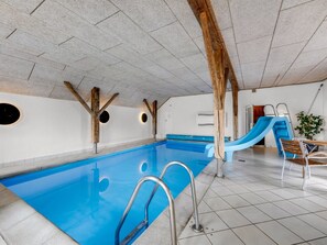 An indoor swimming pool with a blue slide, wooden beams, and a tiled floor. - "Cornelius" - 900m from the sea by Interhome (Ulfborg)