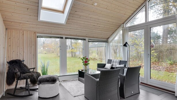 A sunlit room with a high ceiling, large sliding glass doors, wicker furniture, and a rocking chair. - "Hegge" - 300m from the sea by Interhome (Væggerløse)