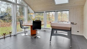 A spacious room with a wooden ceiling, large windows, a foosball table, a dining table with chairs, and a vase with flowers. - "Hegge" - 300m from the sea by Interhome (Væggerløse)