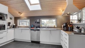 A modern kitchen with white cabinetry, a central island, a skylight, and a view of the outdoors. - "Hegge" - 300m from the sea by Interhome (Væggerløse)