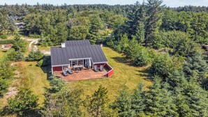 Una casa con terraza, rodeada de un bosque denso.