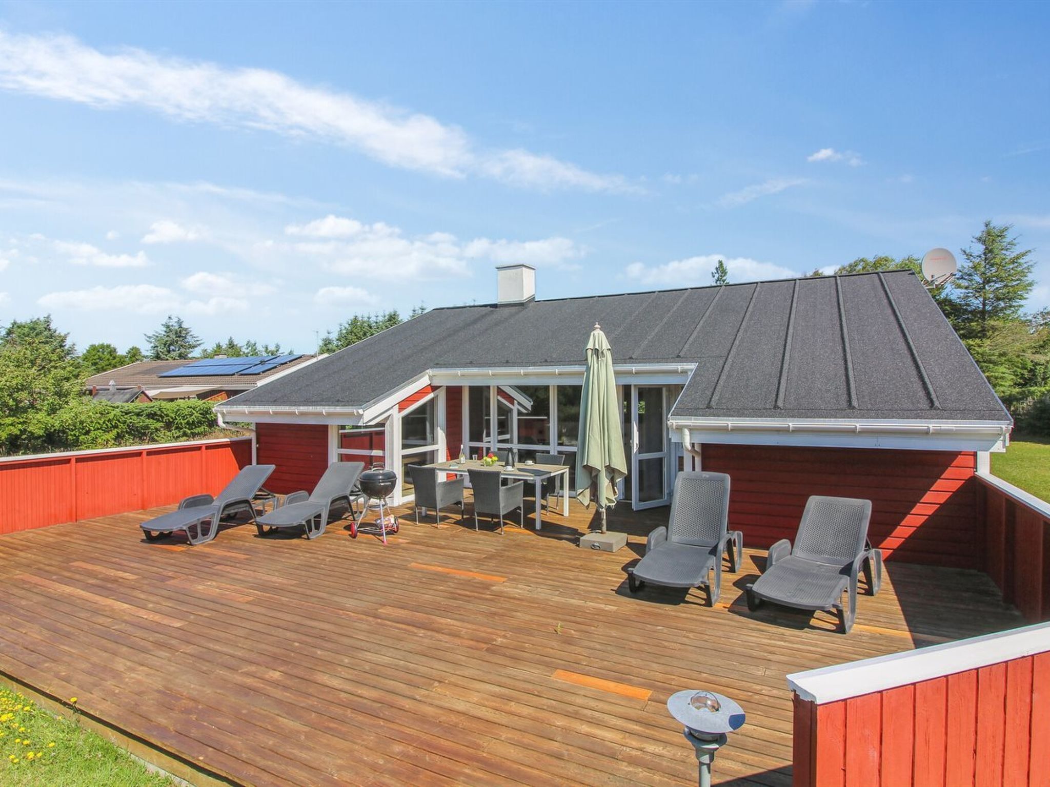 Une terrasse extérieure couverte, équipée d’une table et de chaises, d’un barbecue et d’une pergola.