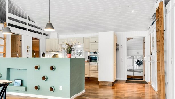 Una cocina amplia con una isla central, suelo de madera y una lámpara colgante moderna.