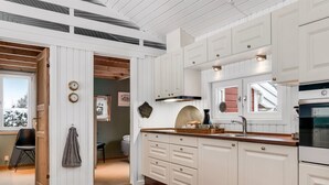 Una cocina con armarios blancos, encimeras de madera y horno empotrado.
